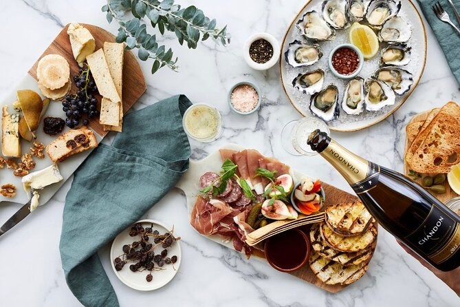 A grazing board of cheese, charcuterie and oysters beside a bottle of Chandon