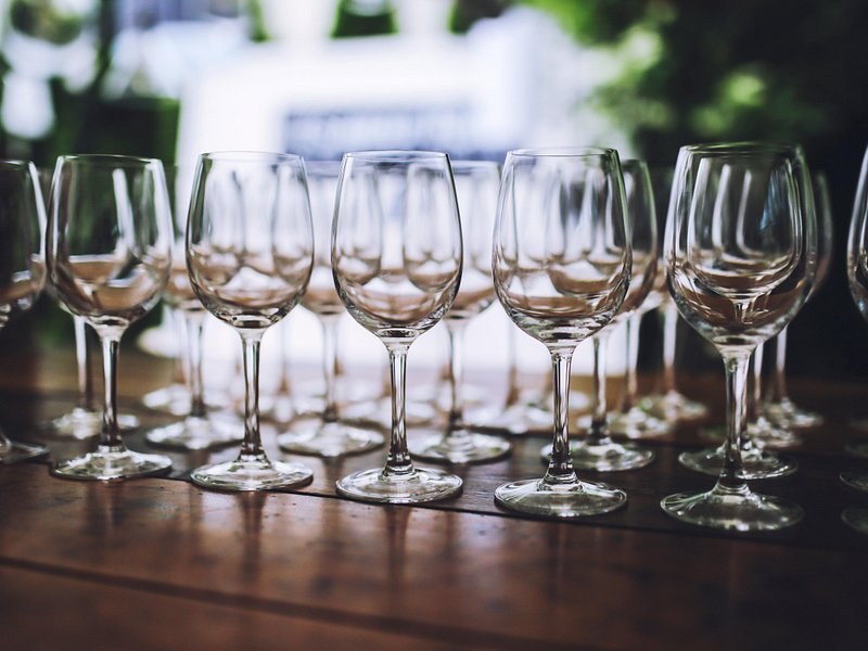 Rows of clean wine glasses set out along a bar before a tasting
